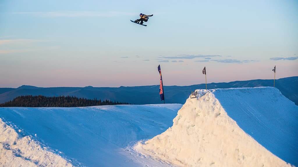 Snowboarder hitting a jump at the Unbound Terrain Park at Mammoth Mountain in California