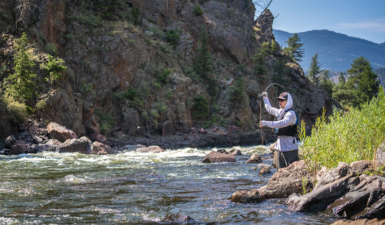 Man casting a fishing line at a river near Winter Park Resort in Colorado
