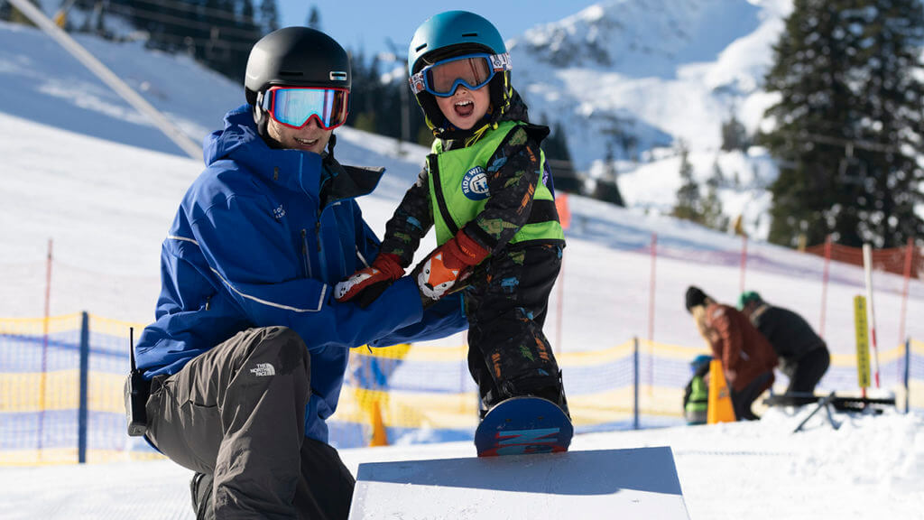 Instructor teaching a young boy how to snowboard at Burton Riglet Park at Squaw Valley