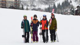 Four women in the twenties getting ready to ski and snowboard at Steamboat in Colorado