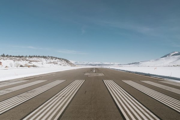 Empty runway surrounded by snow covered mountains at Mammoth Mountain Airport. Fly to the slopes