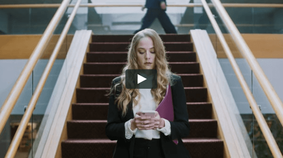 A blond-haired young woman is looking at her smartphone while standing at the bottom of a set of stairs. Last video in the "It's Not Winter" series.
