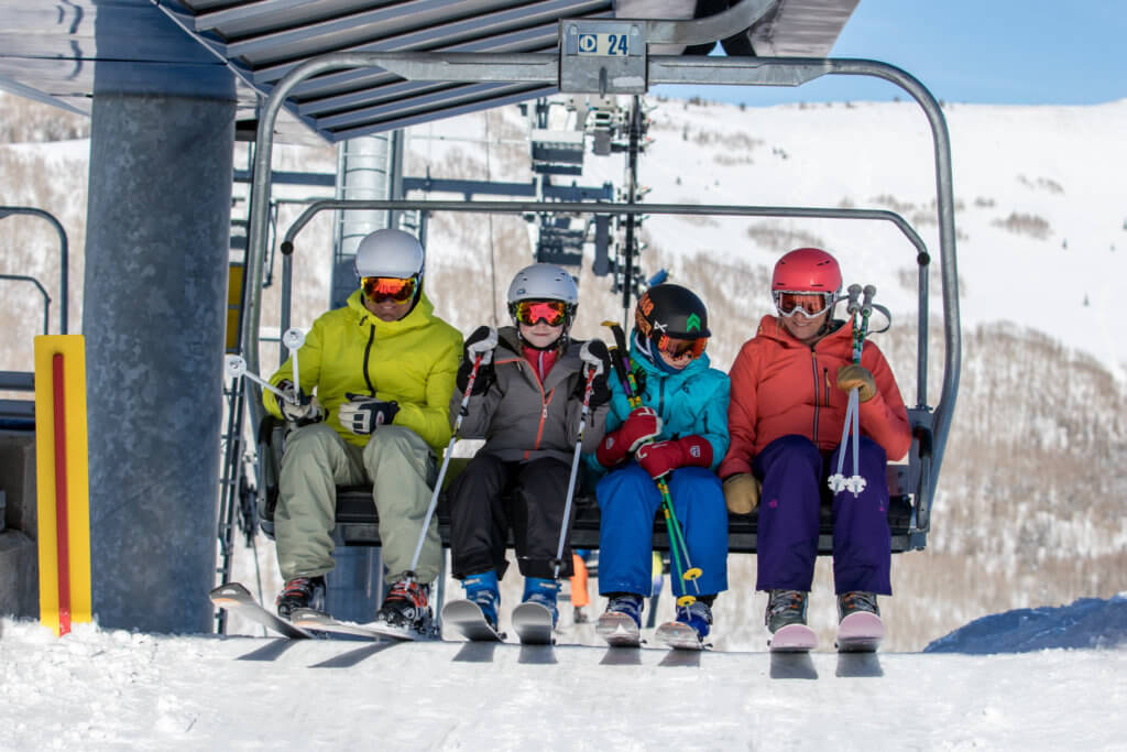 A family dressed in ski gear getting off a ski lift
