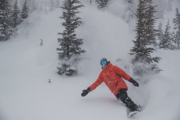 Snowboarder going through powder on a snowy day at Mammoth Mountain
