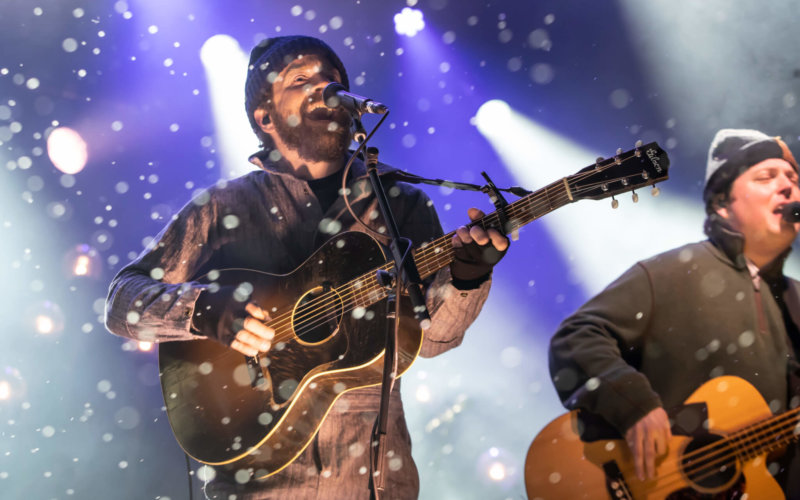 Two men holding guitars singing into microphones at the WinterWonderGrass music festival