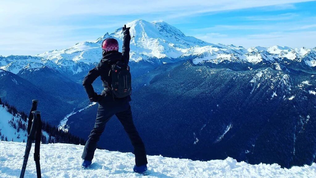 Skier standing on top of a ski run at Crystal Mountain with Mt. Rainier in the background