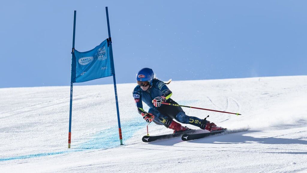 Mikaela Shiffrin racing down a ski slope and turning around a ski gate