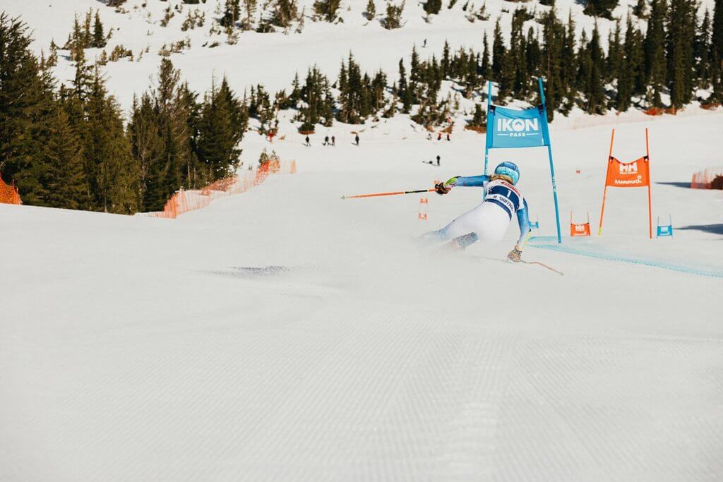 Female ski racer going around a ski gate down a steep run at Mammoth Mountain