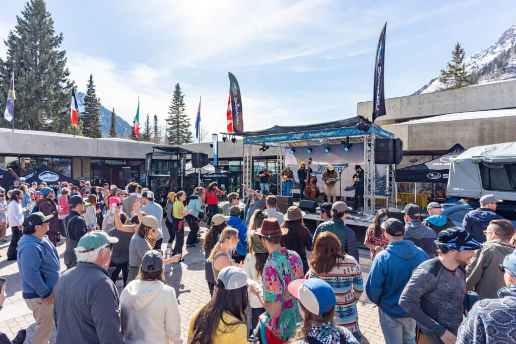 A crowd at the base of a ski resort listening to a band perform