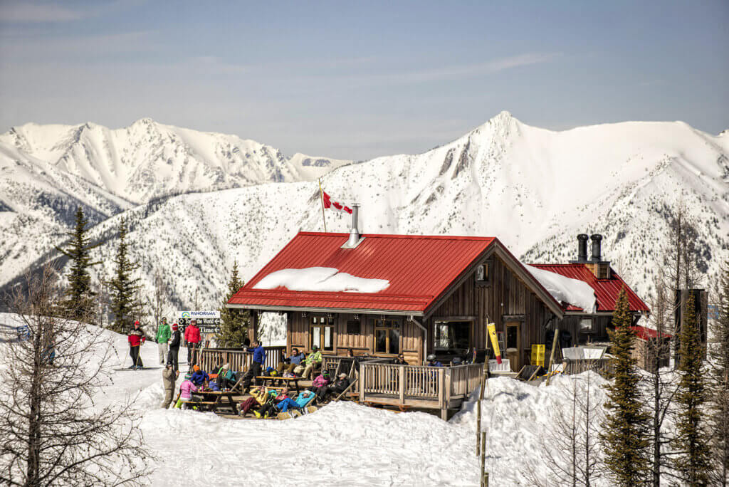 A mountain hut with a group of people sitting on the patio