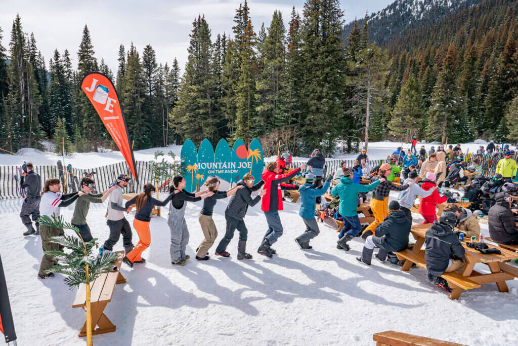 A conga line of people in ski gear at the base of a ski resort