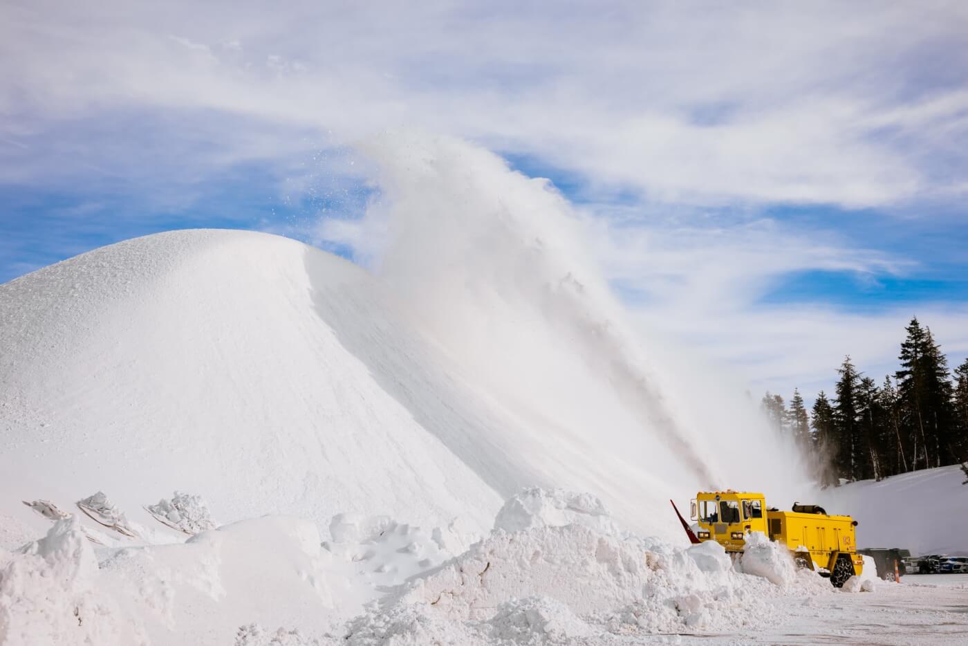 Snow plow blowing snow onto a very high snow pile