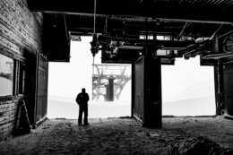 Man stands inside of ski lift operation and looks out at the mountain.