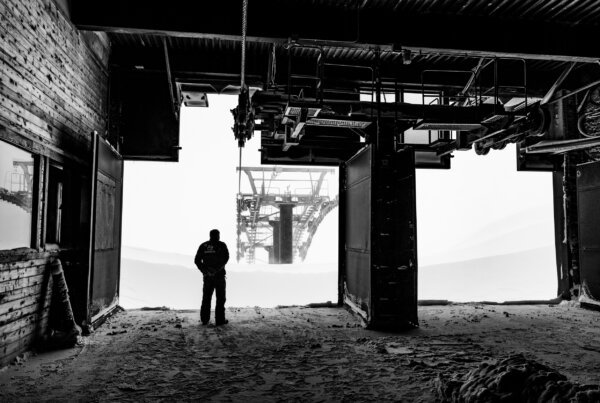 Man stands inside of ski lift operation and looks out at the mountain.