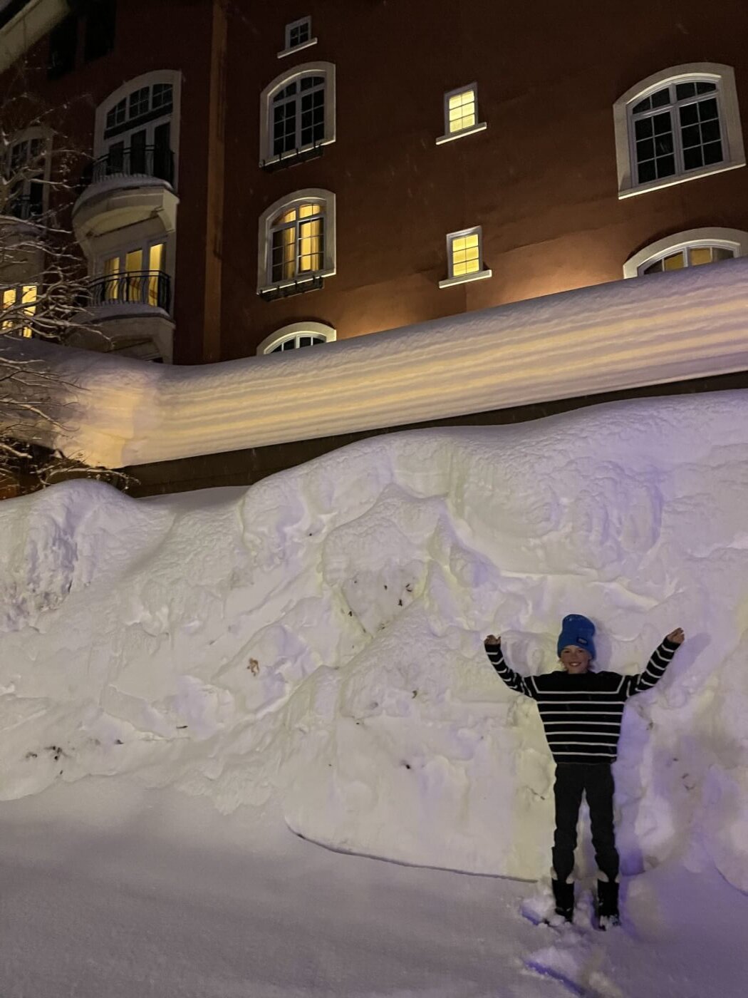 a kid standing in front of a pile of snow twice their height