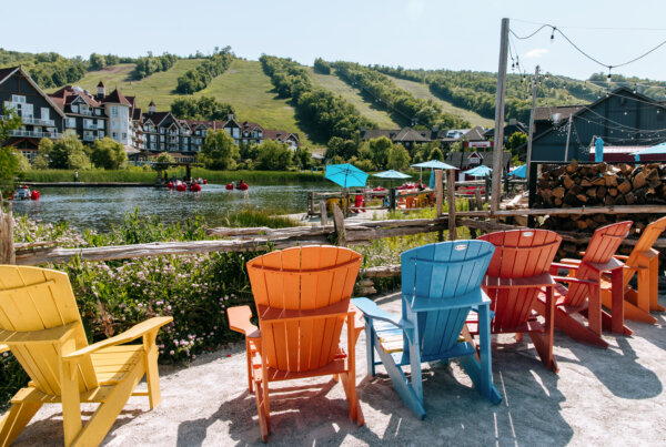 Group of colorful chairs facing a lake at the base of a mountain.