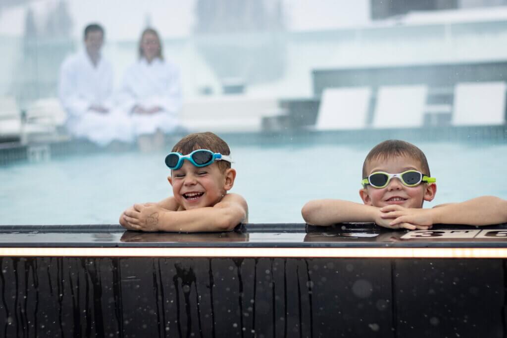 Two children wearing googles playing in a hotel pool.