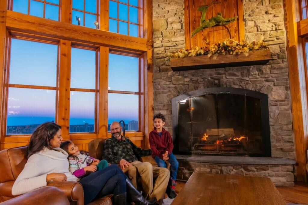 Family relaxing in front of the fireplace in their lodging accommodations.