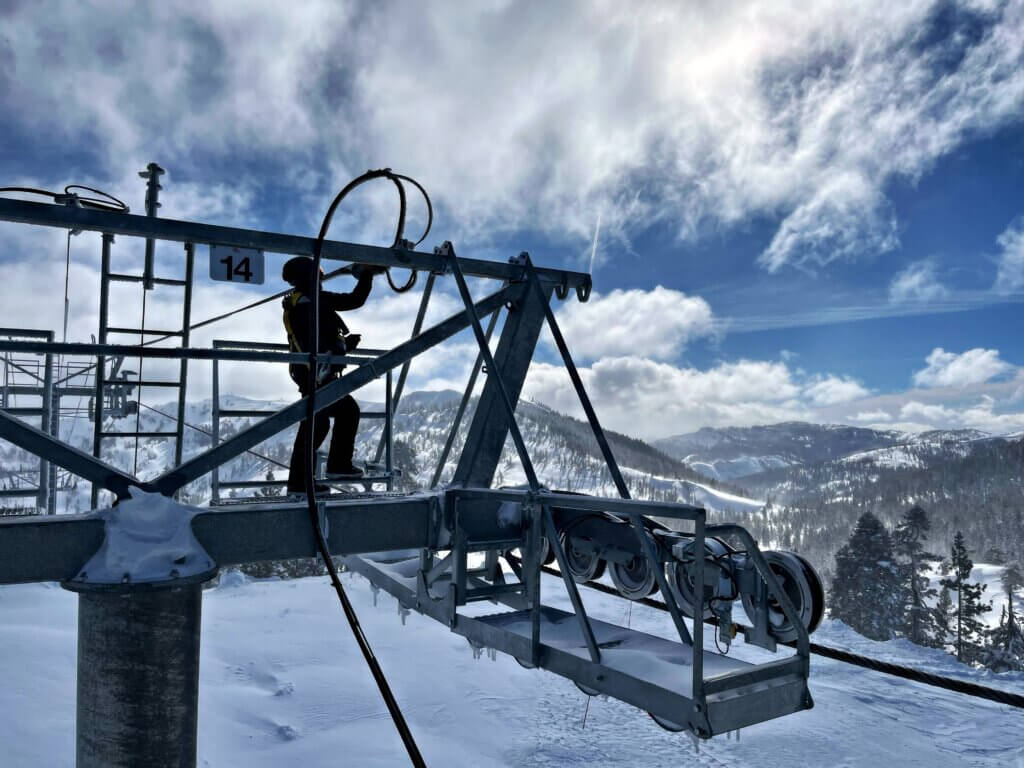 Person standing on the top of a chairlift pole working