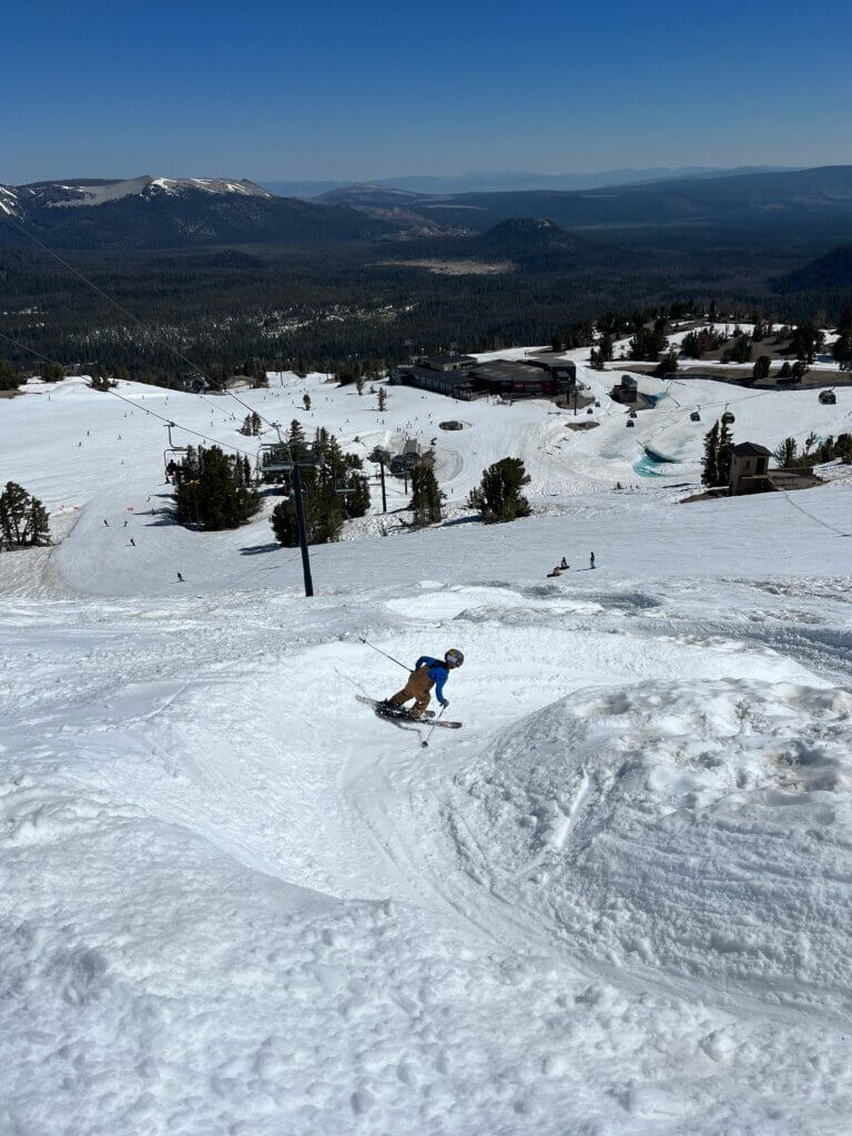 Person skiing down a snowy run on a sunny day