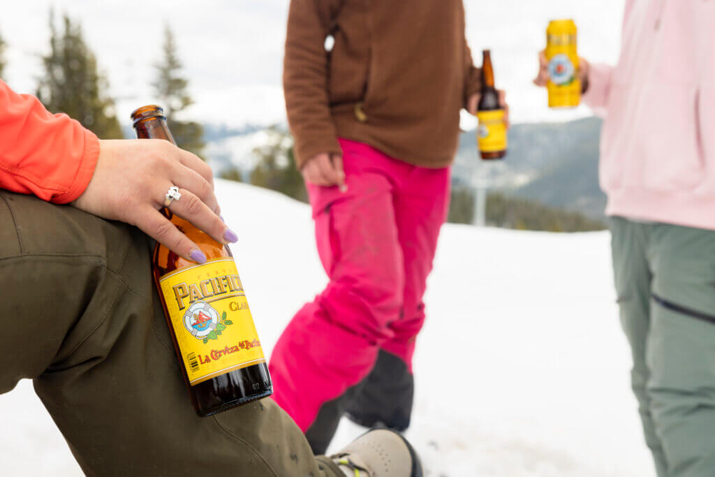 Three people drinking Pacifico on the slopes.