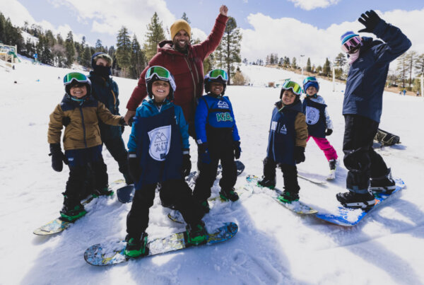 Group of kids out snowboarding with two adults.