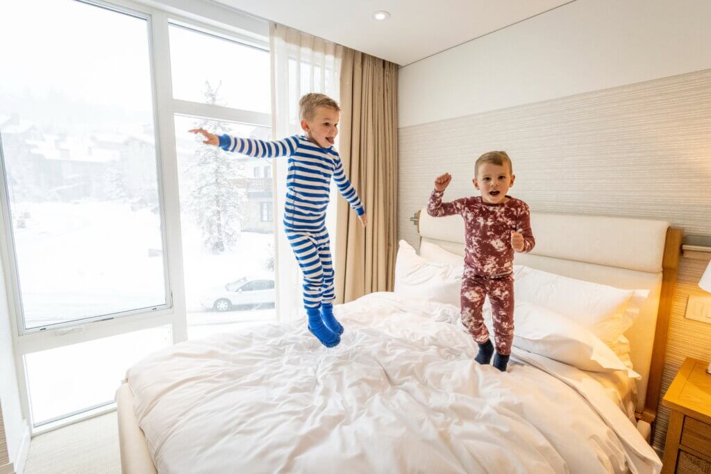 Two children jumping on a bed.