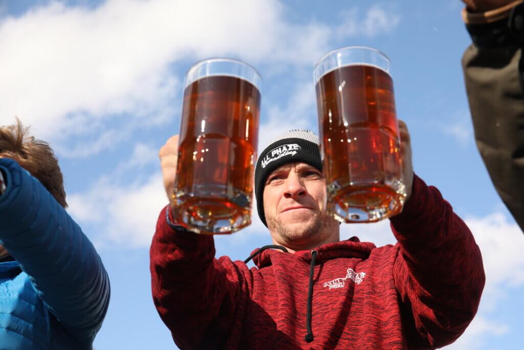 Stein holding competition contestant holds up two full beer steins.