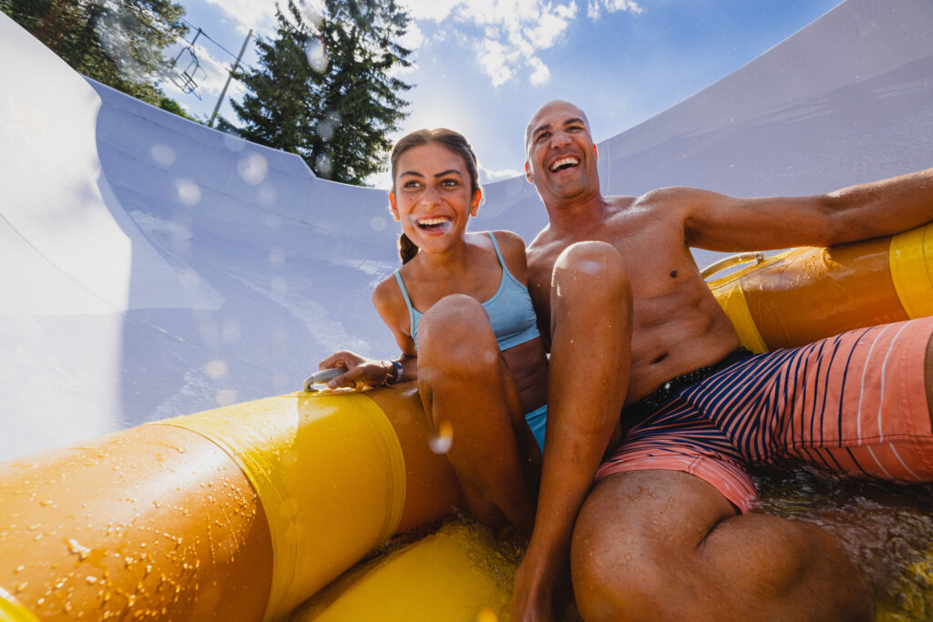 Adult and a child going down a waterslide in an inflatable tube.