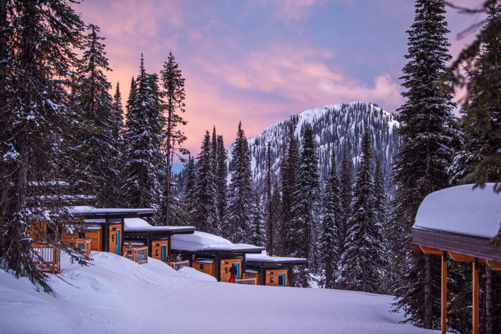 Ski in/ski out cabins on a snow covered mountain at sunset.