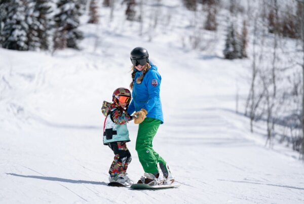 Snowboard instructor helping a child during a lesson.