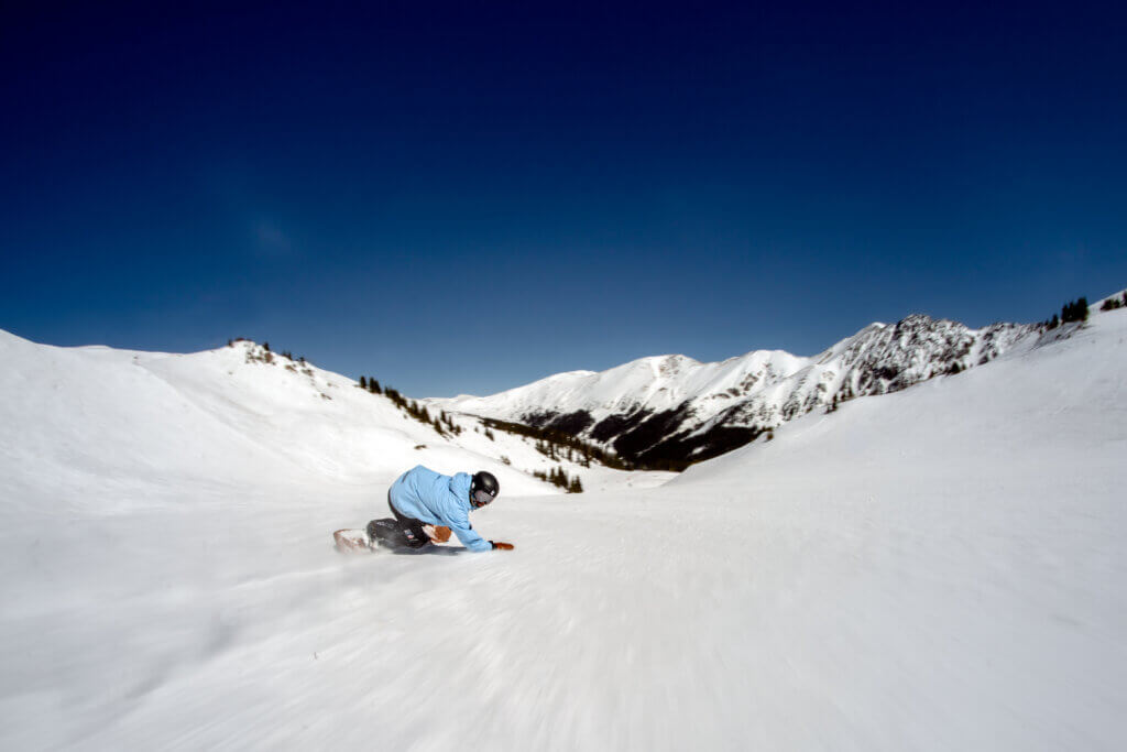 Person snowboarding down a snow covered mountain.