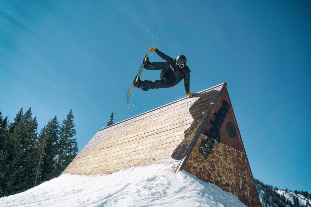 Snowboarder on a terrain park wall.