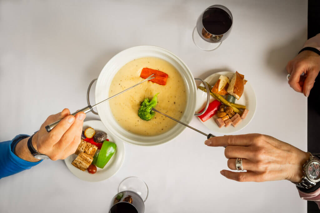 Two people dipping food into fondue.