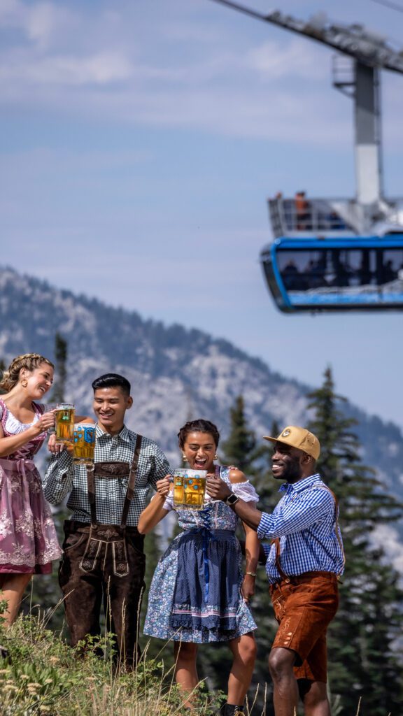 People drinking beer on a mountain in front of a gondola car