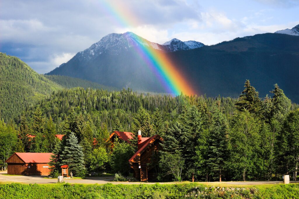 A lodge in the mountains with a rainbow above