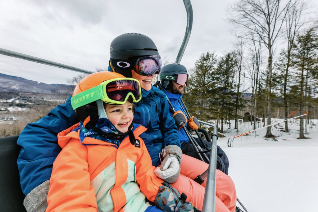 kid and two adults sitting on chairlift
