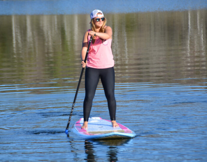 Young woman standing on a paddle board in a lake at Stratton Mountain