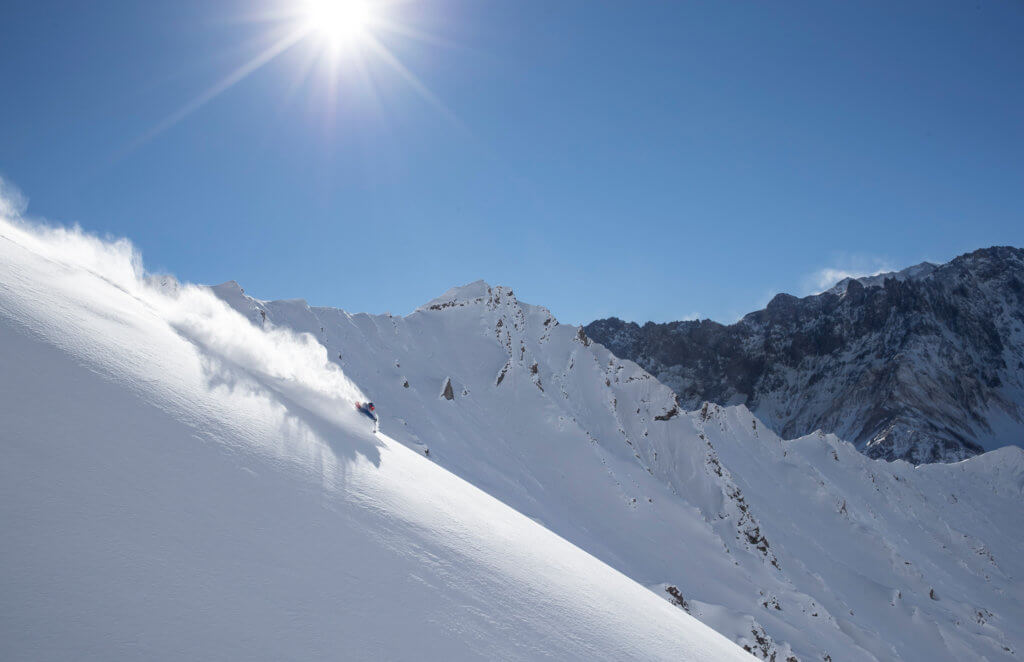 A skier gliding down a fresh powder run on a sunny, blue sky day