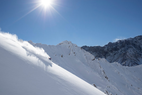 A skier gliding down a fresh powder run on a sunny, blue sky day