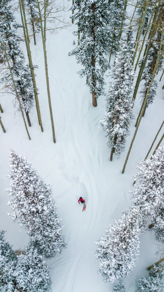 drone shot of a solo skier gliding through the trees at Deer Valley