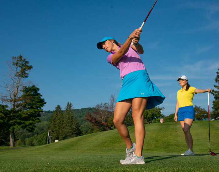 Two women playing golf in brightly colored outfits on a sunny day at Stratton Mountain