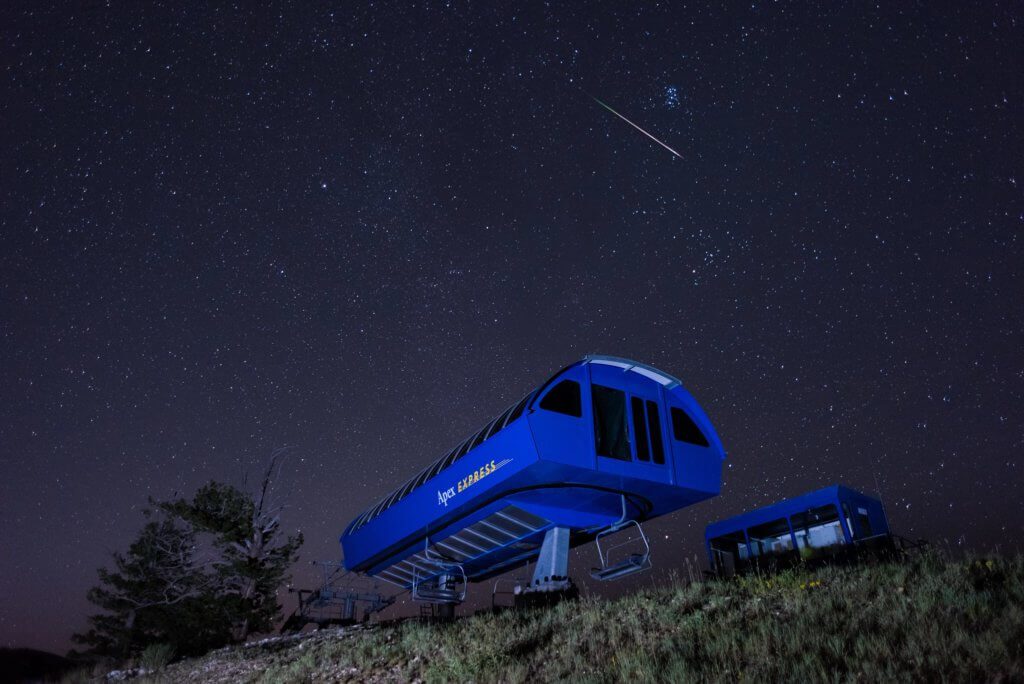 Image of the sky at night lit up with stars with a ski lift in the foreground.