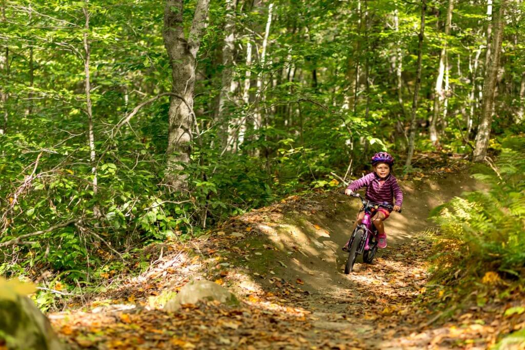 Young girl biking on a dirt trail at Sugarbush resort in Vermont