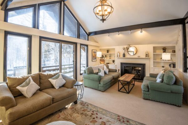 a mountain living room with large high windows, couches, and a fireplace