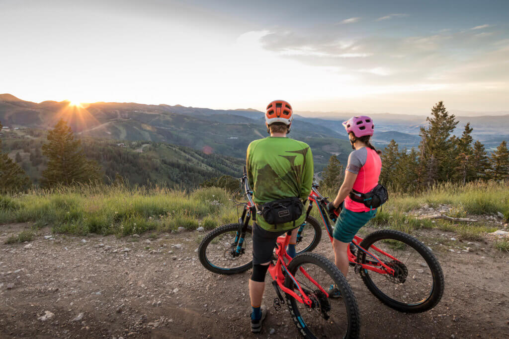 Two mountain bike riders taking in the sunset views from the trail at Deer Valley Resort in Park City, Utah